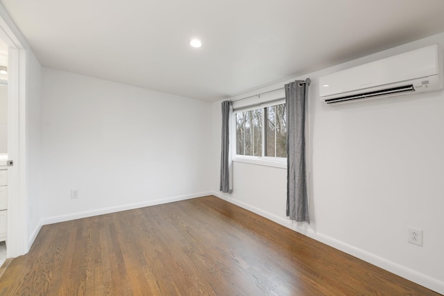 unfurnished room with hardwood / wood-style flooring and an AC wall unit