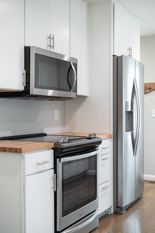 kitchen featuring white cabinetry, stainless steel appliances, dark wood-type flooring, and butcher block countertops