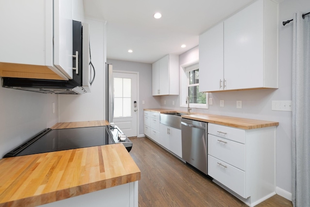 kitchen with dark wood-type flooring, sink, butcher block countertops, stainless steel dishwasher, and white cabinets