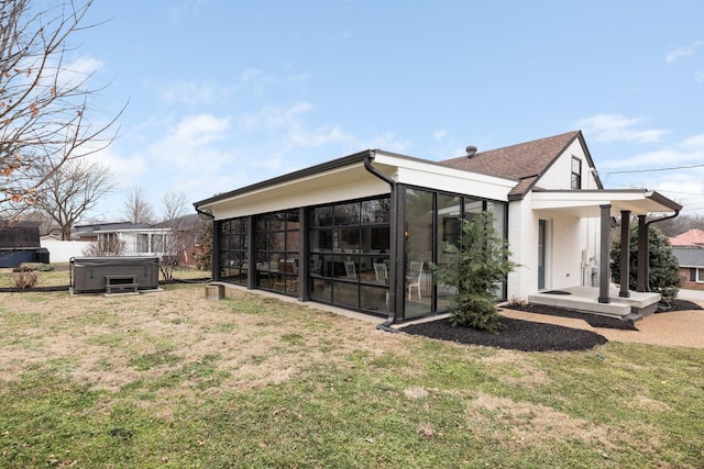 back of house featuring a yard, a hot tub, and a sunroom