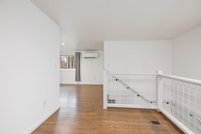 unfurnished room featuring wood-type flooring and a wall mounted AC