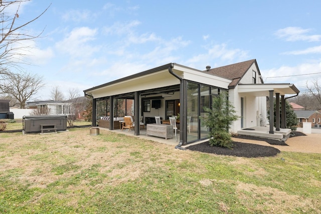 back of property featuring outdoor lounge area, a yard, a hot tub, a sunroom, and a patio area