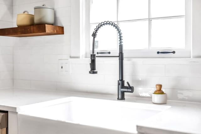 interior details with white cabinetry, sink, and backsplash