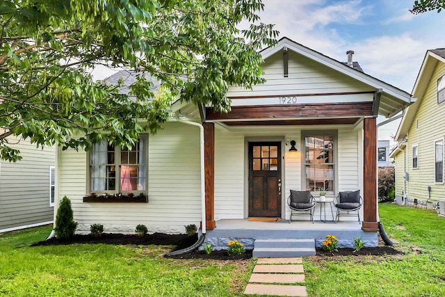 bungalow featuring covered porch and a front lawn