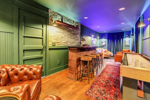 bar with light hardwood / wood-style flooring and green cabinets