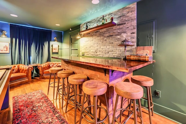 bar featuring brick wall and light hardwood / wood-style flooring