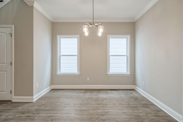 unfurnished room with ornamental molding, plenty of natural light, a chandelier, and light hardwood / wood-style flooring