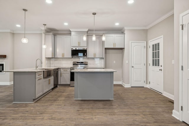 kitchen featuring appliances with stainless steel finishes, sink, hanging light fixtures, kitchen peninsula, and light stone countertops