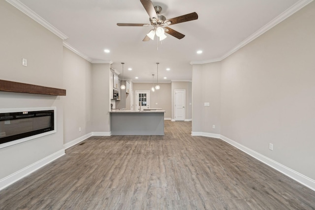 unfurnished living room with crown molding, ceiling fan, and dark hardwood / wood-style flooring