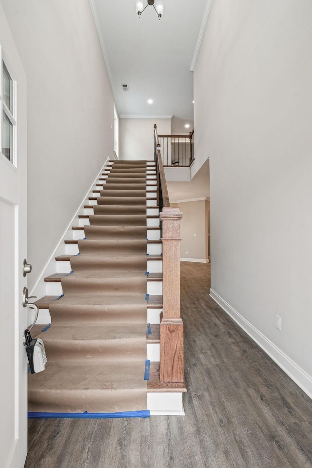 stairway with ornamental molding and hardwood / wood-style floors