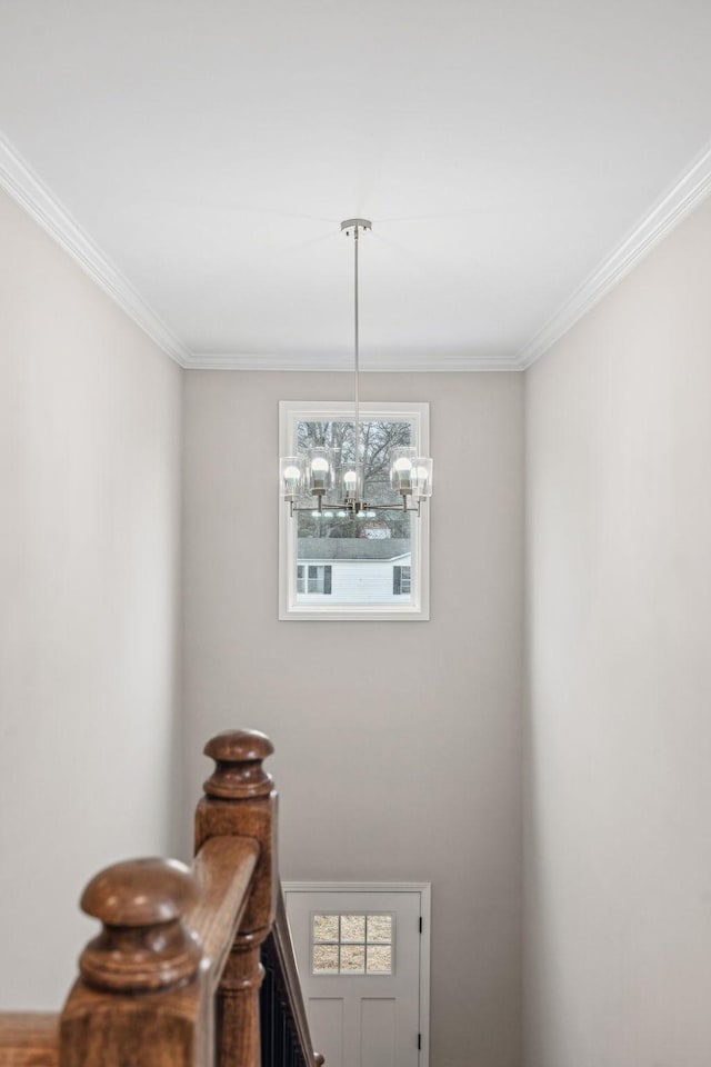 stairway with crown molding and an inviting chandelier