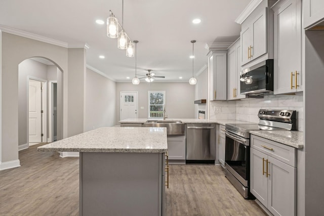 kitchen with stainless steel appliances, hanging light fixtures, gray cabinets, and a kitchen bar