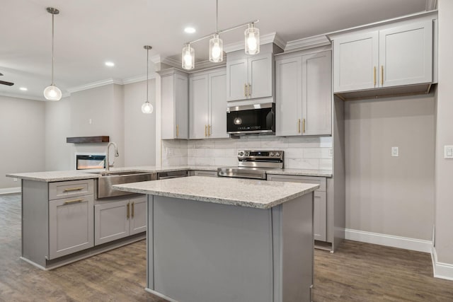 kitchen featuring pendant lighting, sink, stainless steel appliances, a center island, and light stone counters