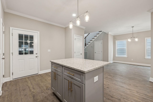 kitchen with decorative light fixtures, gray cabinetry, ornamental molding, a center island, and dark wood-type flooring