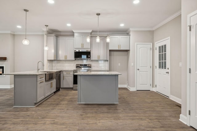 kitchen featuring sink, stainless steel appliances, light stone counters, decorative light fixtures, and kitchen peninsula