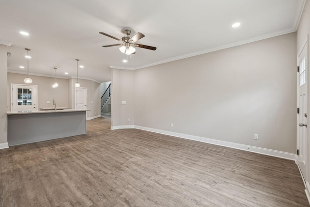 unfurnished living room with crown molding, ceiling fan, dark hardwood / wood-style floors, and sink