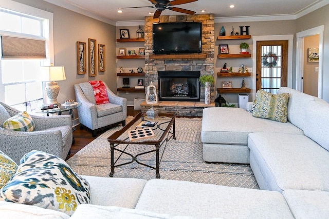 living room featuring crown molding, wood-type flooring, ceiling fan, and a fireplace