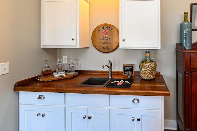 kitchen with white cabinetry, wooden counters, and sink