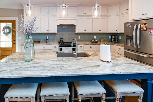 kitchen with premium range hood, decorative light fixtures, a kitchen breakfast bar, and a center island with sink