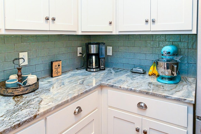 kitchen with white cabinetry, light stone countertops, and tasteful backsplash