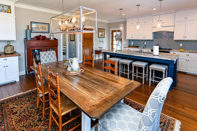 dining area featuring an inviting chandelier, sink, ornamental molding, and dark hardwood / wood-style floors