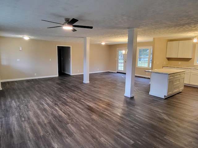 unfurnished living room with ceiling fan, dark hardwood / wood-style floors, and a textured ceiling