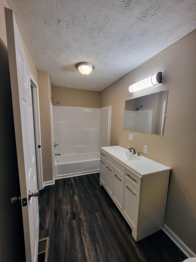 bathroom with hardwood / wood-style flooring, vanity, tub / shower combination, and a textured ceiling