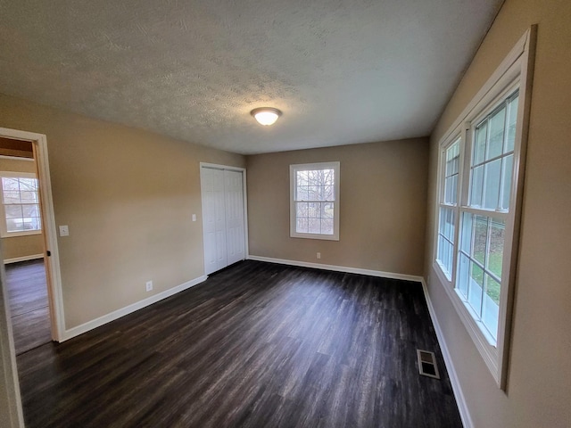 unfurnished room with dark hardwood / wood-style floors and a textured ceiling