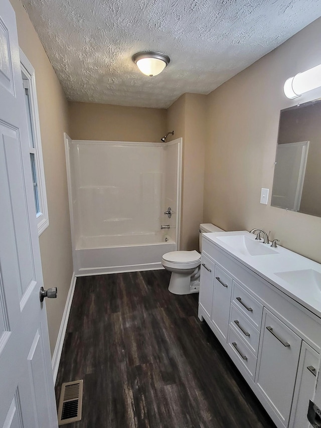 full bathroom featuring bathtub / shower combination, hardwood / wood-style flooring, vanity, toilet, and a textured ceiling