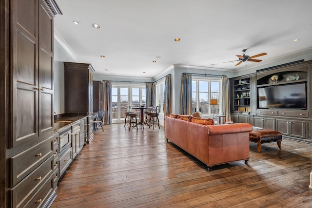 living room featuring dark hardwood / wood-style flooring, built in features, ornamental molding, and ceiling fan