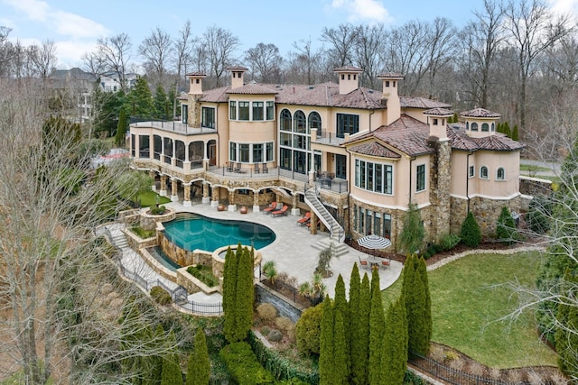 back of house with a balcony, a patio area, and a lawn