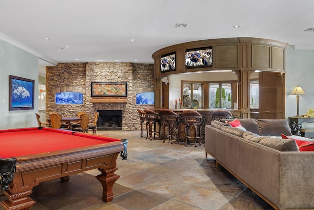 game room with crown molding, indoor bar, a stone fireplace, and billiards