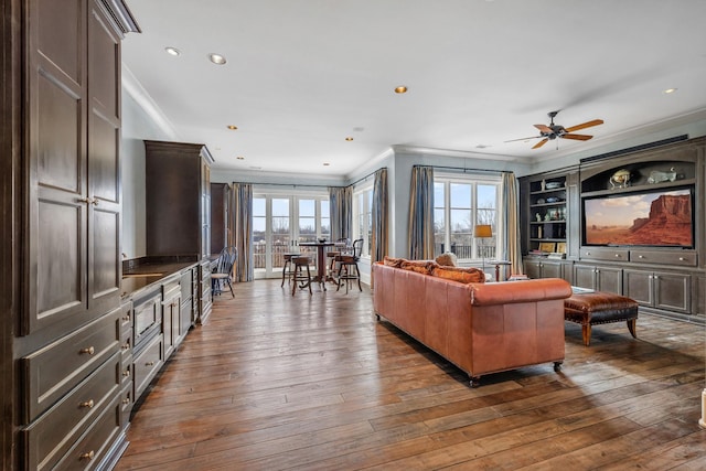 living room featuring dark wood-type flooring, ceiling fan, and ornamental molding