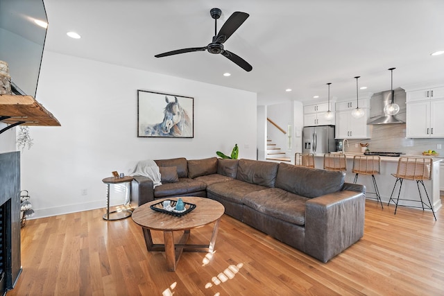 living room featuring sink, light hardwood / wood-style floors, and ceiling fan