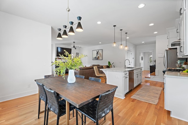 dining area with ceiling fan, sink, and light wood-type flooring