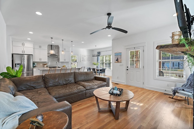 living room featuring sink, light hardwood / wood-style flooring, and ceiling fan