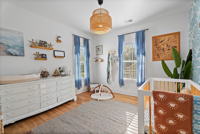 bedroom featuring a nursery area and light wood-type flooring