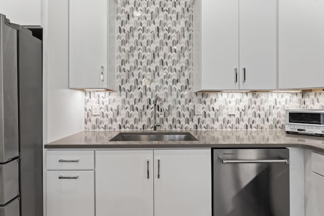 kitchen with white cabinetry, appliances with stainless steel finishes, sink, and backsplash