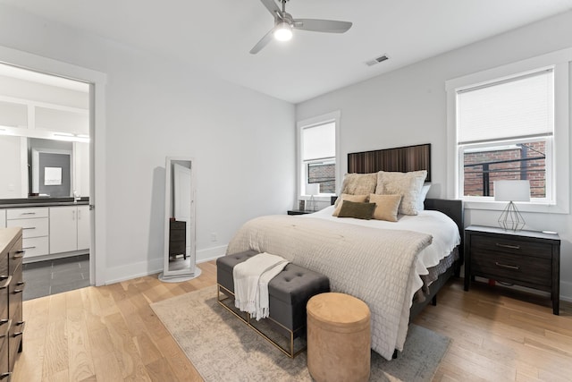 bedroom featuring ensuite bath, light hardwood / wood-style flooring, and ceiling fan