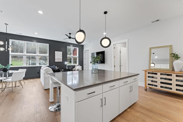 kitchen featuring a center island, pendant lighting, white cabinets, and light hardwood / wood-style floors