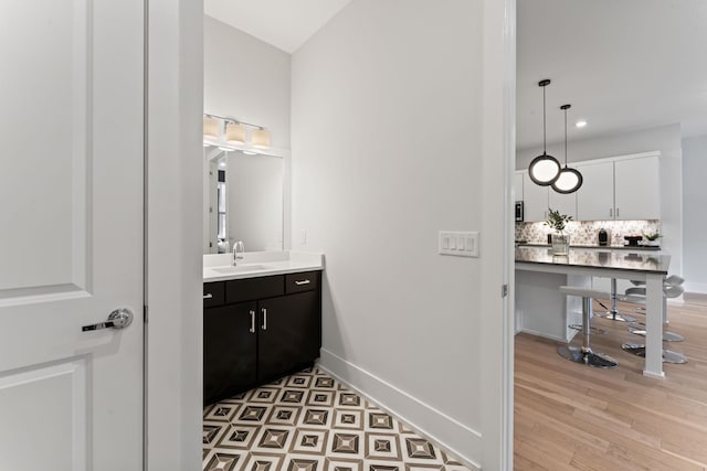 bathroom with hardwood / wood-style flooring, vanity, and decorative backsplash