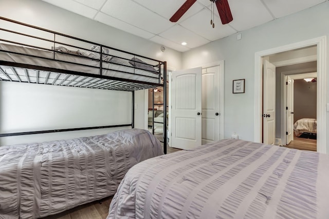 bedroom featuring ceiling fan, hardwood / wood-style floors, and a drop ceiling