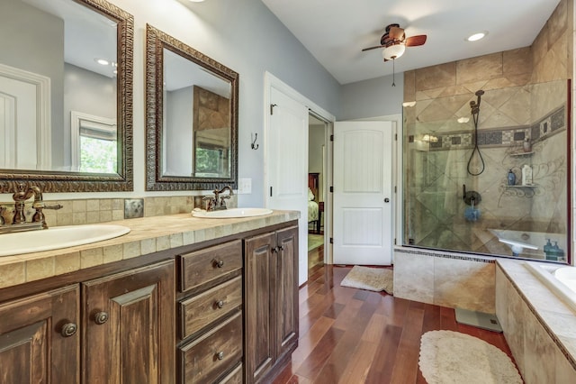 bathroom featuring hardwood / wood-style flooring, ceiling fan, vanity, tasteful backsplash, and independent shower and bath