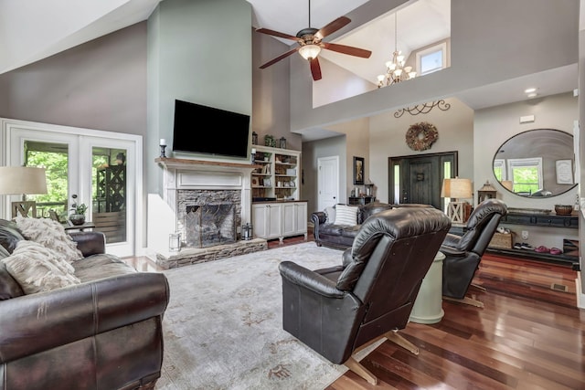 living room with high vaulted ceiling, a stone fireplace, hardwood / wood-style floors, and a notable chandelier