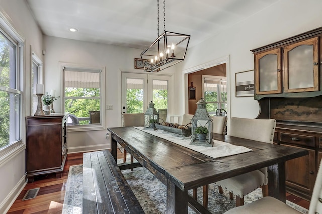 dining area featuring dark wood-type flooring, an inviting chandelier, and a wealth of natural light