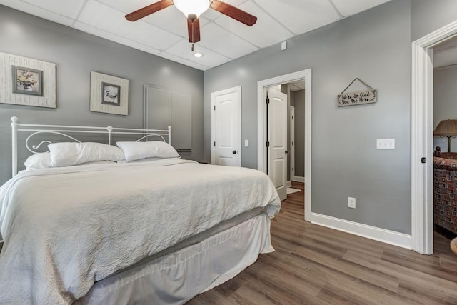 bedroom featuring wood-type flooring, ceiling fan, and a paneled ceiling