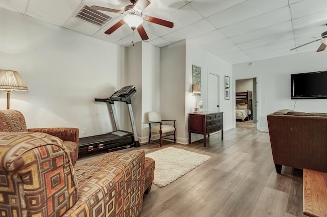 exercise room featuring ceiling fan, a paneled ceiling, and wood-type flooring