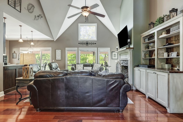 living room featuring ceiling fan, a stone fireplace, dark hardwood / wood-style floors, and a healthy amount of sunlight