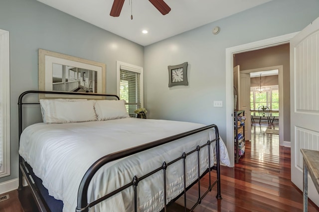 bedroom with dark hardwood / wood-style floors and ceiling fan with notable chandelier