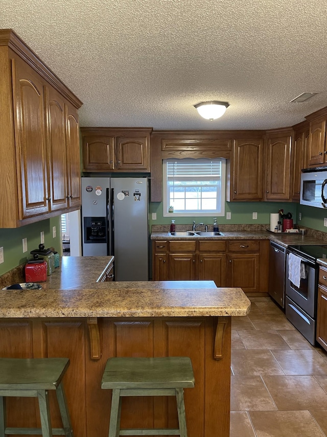 kitchen featuring stainless steel appliances, kitchen peninsula, sink, and a breakfast bar area